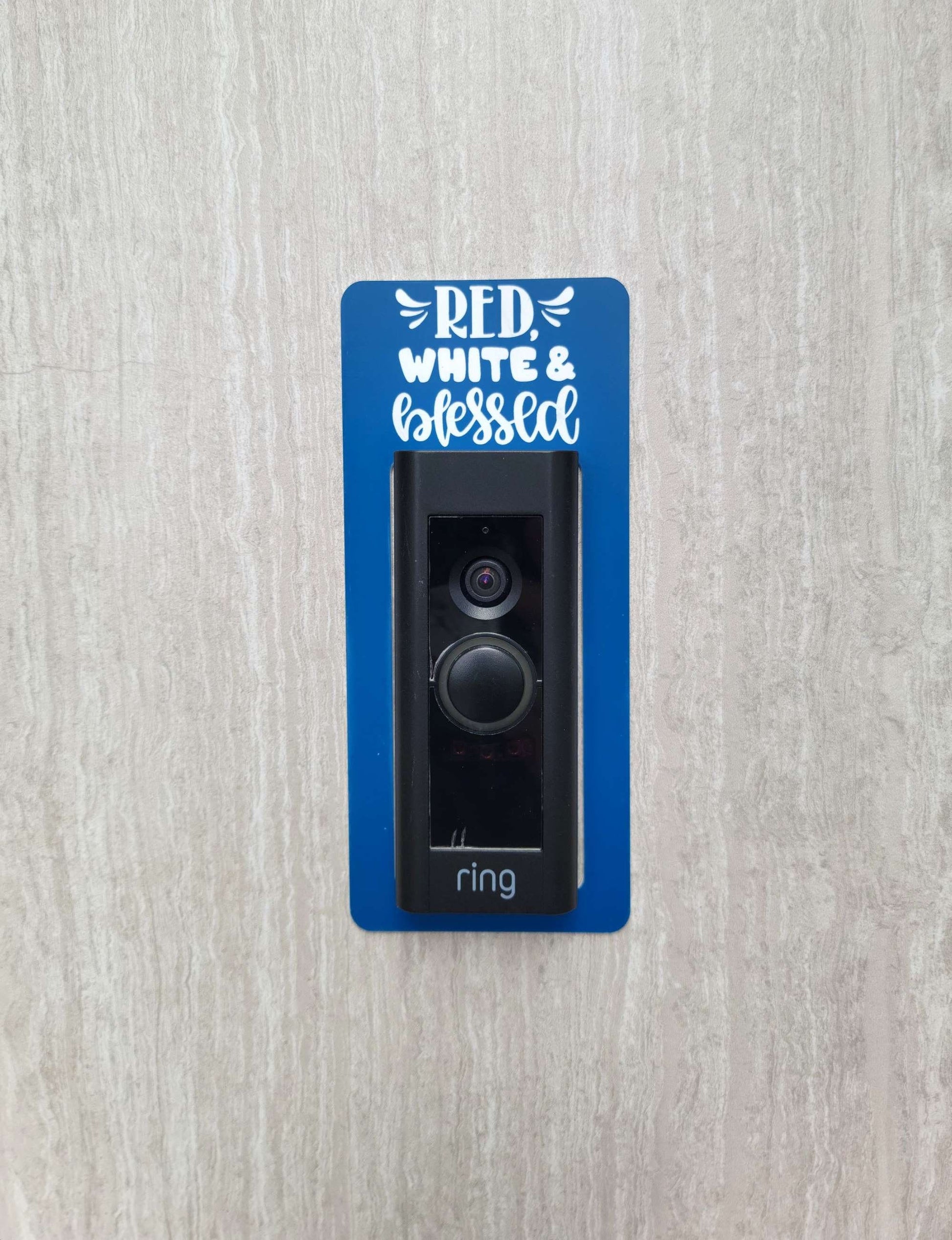 Blue laminate doorbell surround with white lettering stating red, white and blessed on gray background