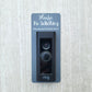 Gray laminate rectangle that fits around a Ring doorbell with white laser engraved lettering stating Please No Soliciting Seriously Don't Make It Weird on a neutral background