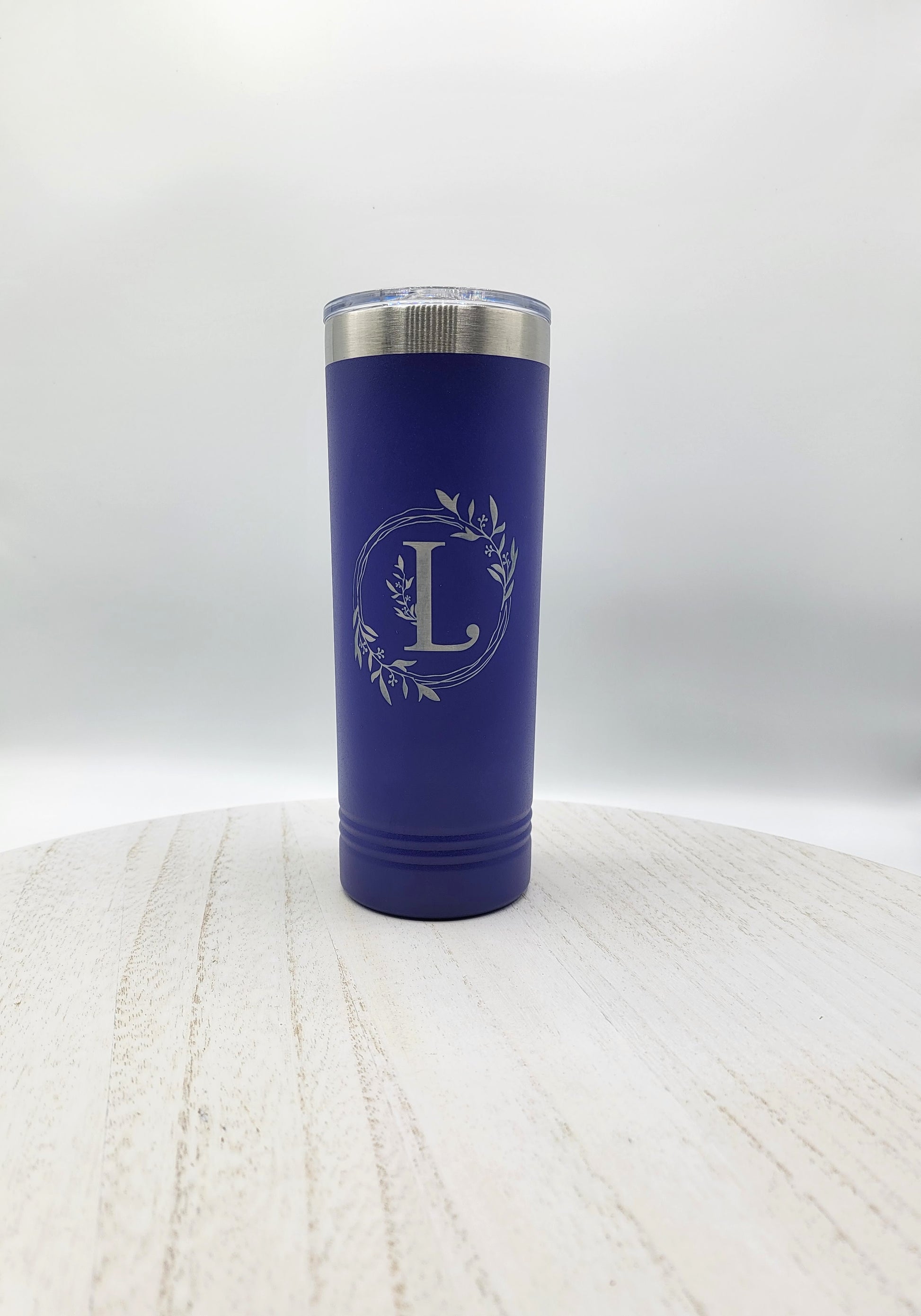 Navy blue skinny tumbler with floral wreath and letter L in silver on white background