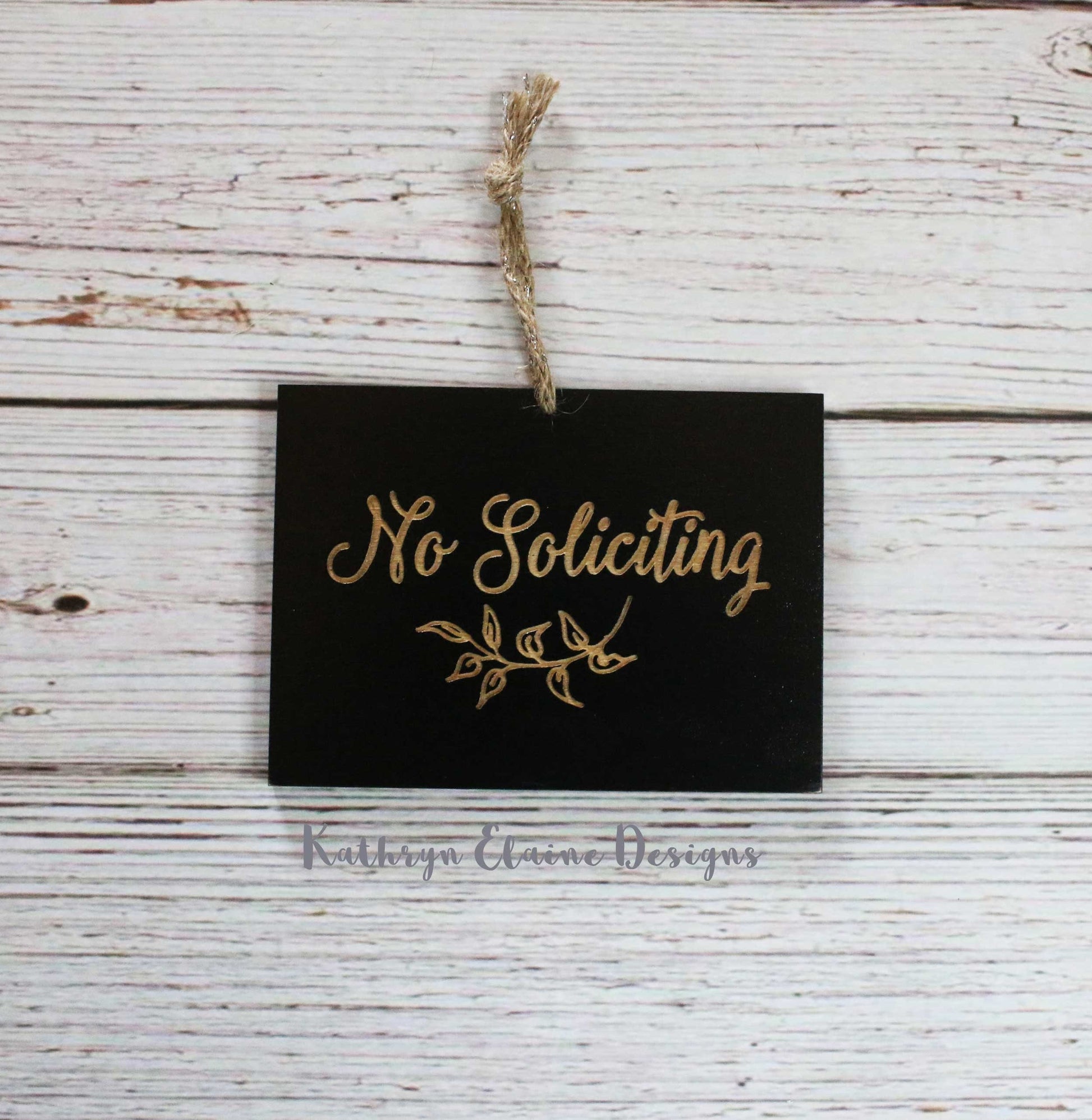Black rectangle laser engrave no soliciting sign with leaf design and twine hanger on white wood background