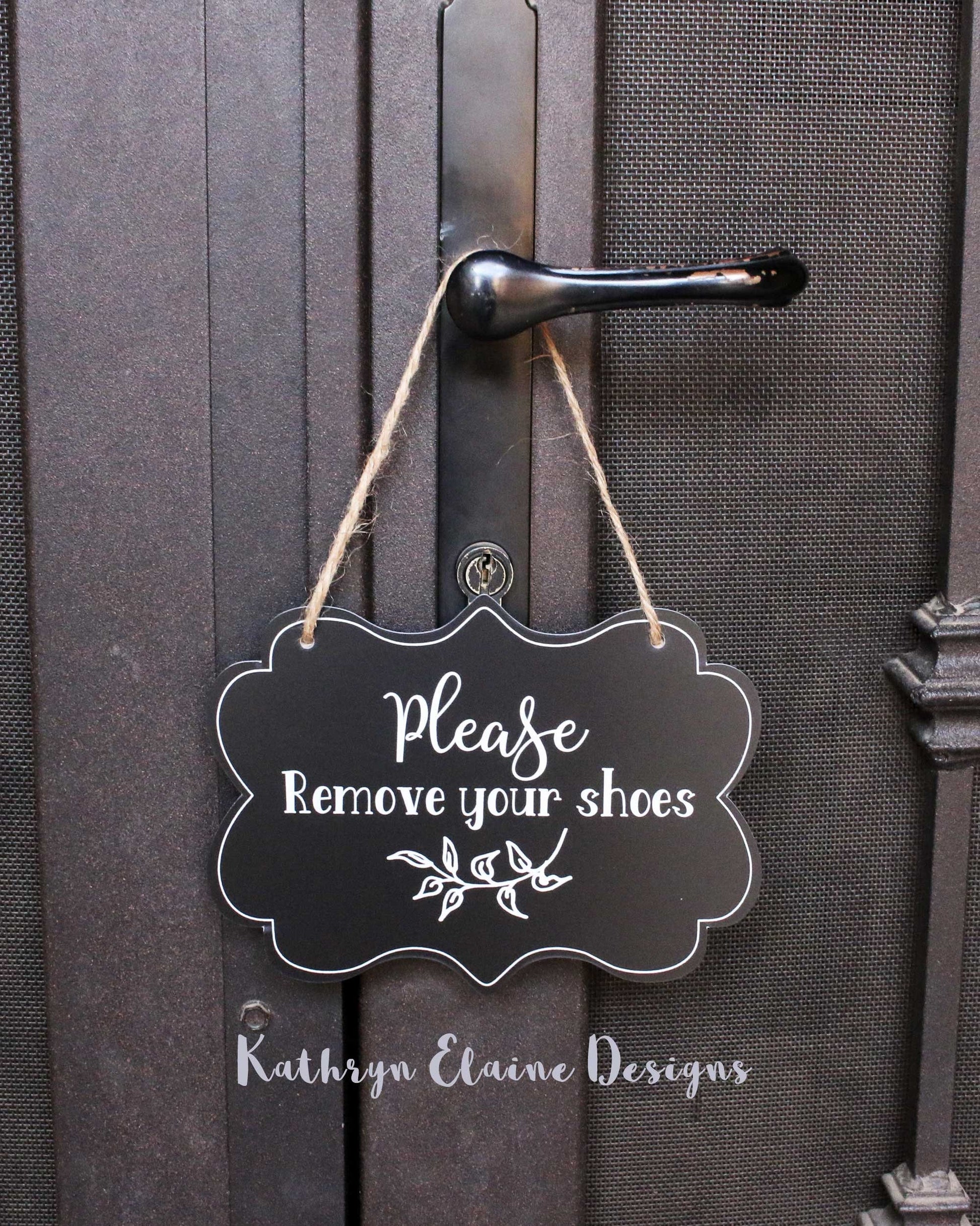 Black laminate scalloped edge sign with white lettering stating Please remove your shoes with leaf design and border on screen door