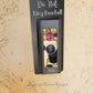Black laminate doorbell surround with white lettering stating Do Not Ring Doorbell on Ring doorbell and tan background
