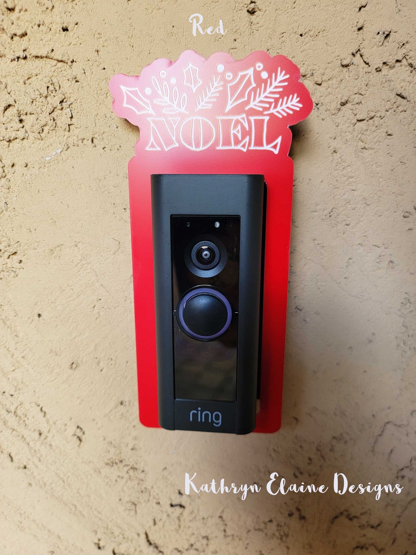 Red laminate doorbell surround with white lettering saying Noel and holly, leaf design around ring doorbell on tan background.