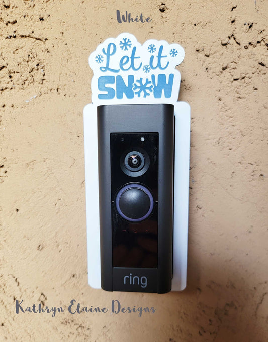 White doorbell surround with blue snowflakes and lettering stating let it snow on ring doorbell and tan background