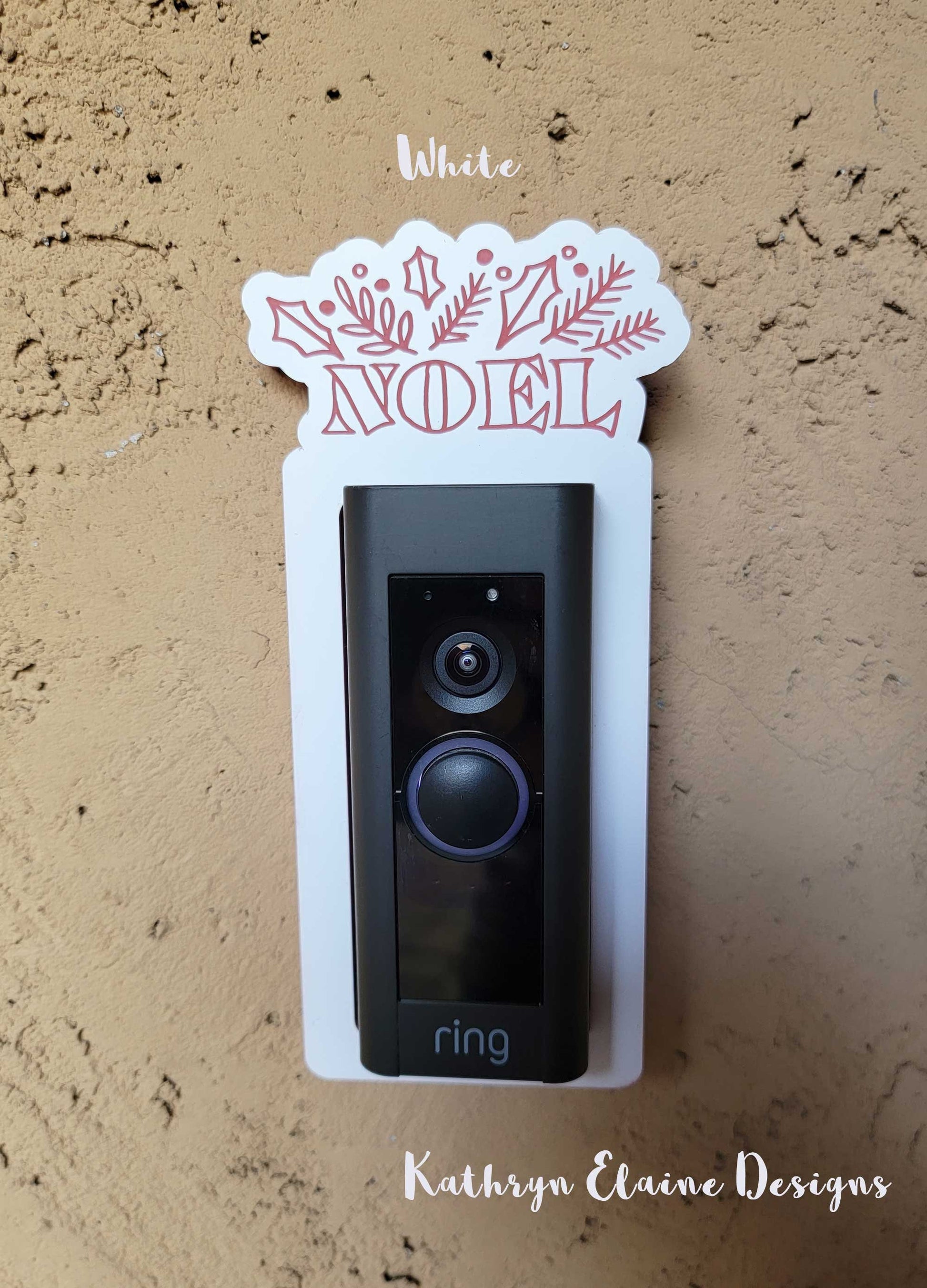 White laminate doorbell surround with red lettering saying Noel and holly, leaf design around ring doorbell on tan background.