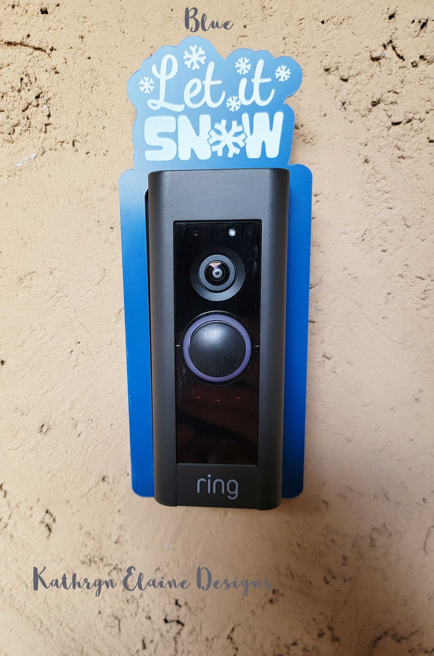Blue doorbell surround with white snowflakes and lettering stating let it snow on ring doorbell and tan background