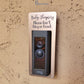 Bronze laminate rectangle around Ring doorbell that says Baby Sleeping Please Don't Ring or Knock in gray lettering against tan stucco background