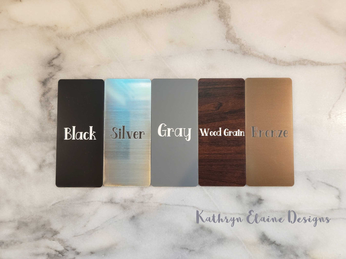 5 laminate color choices: black with white lettering, silver with black lettering, gray with white lettering, wood grain with white lettering, and bronze with gray lettering on marble background