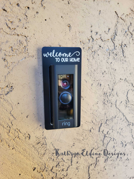 Black laminate doorbell surround stating Welcome to our home in white lettering around Ring doorbell on tan background
