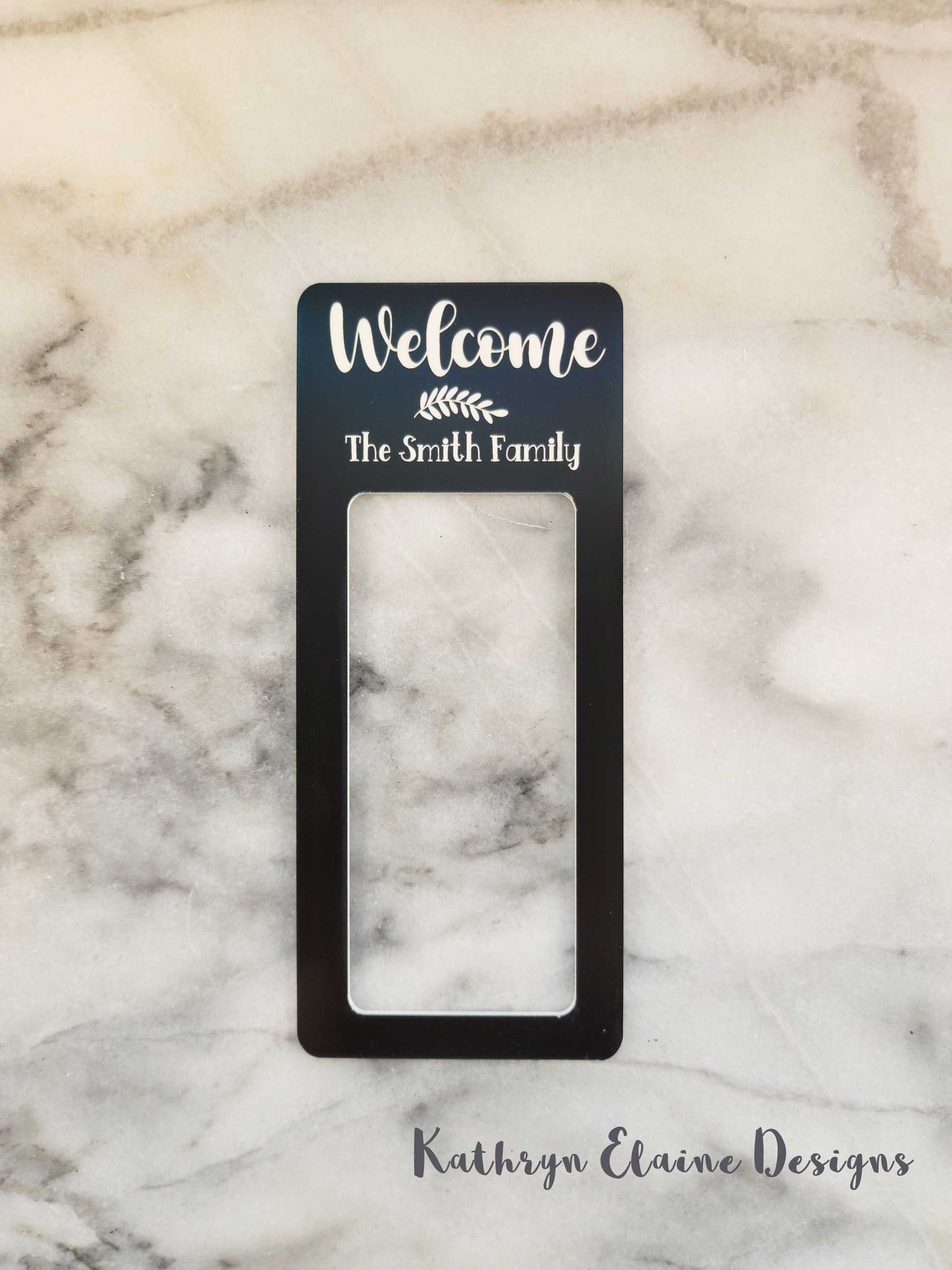 Black laminate doorbell surround stating Welcome (leaf design) the Smith Family in white writing on marble background.