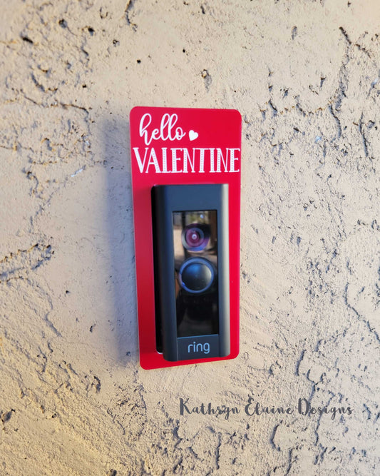 Red laminate doorbell surround with white heart and lettering saying hello Valentine on ring doorbell and tan background