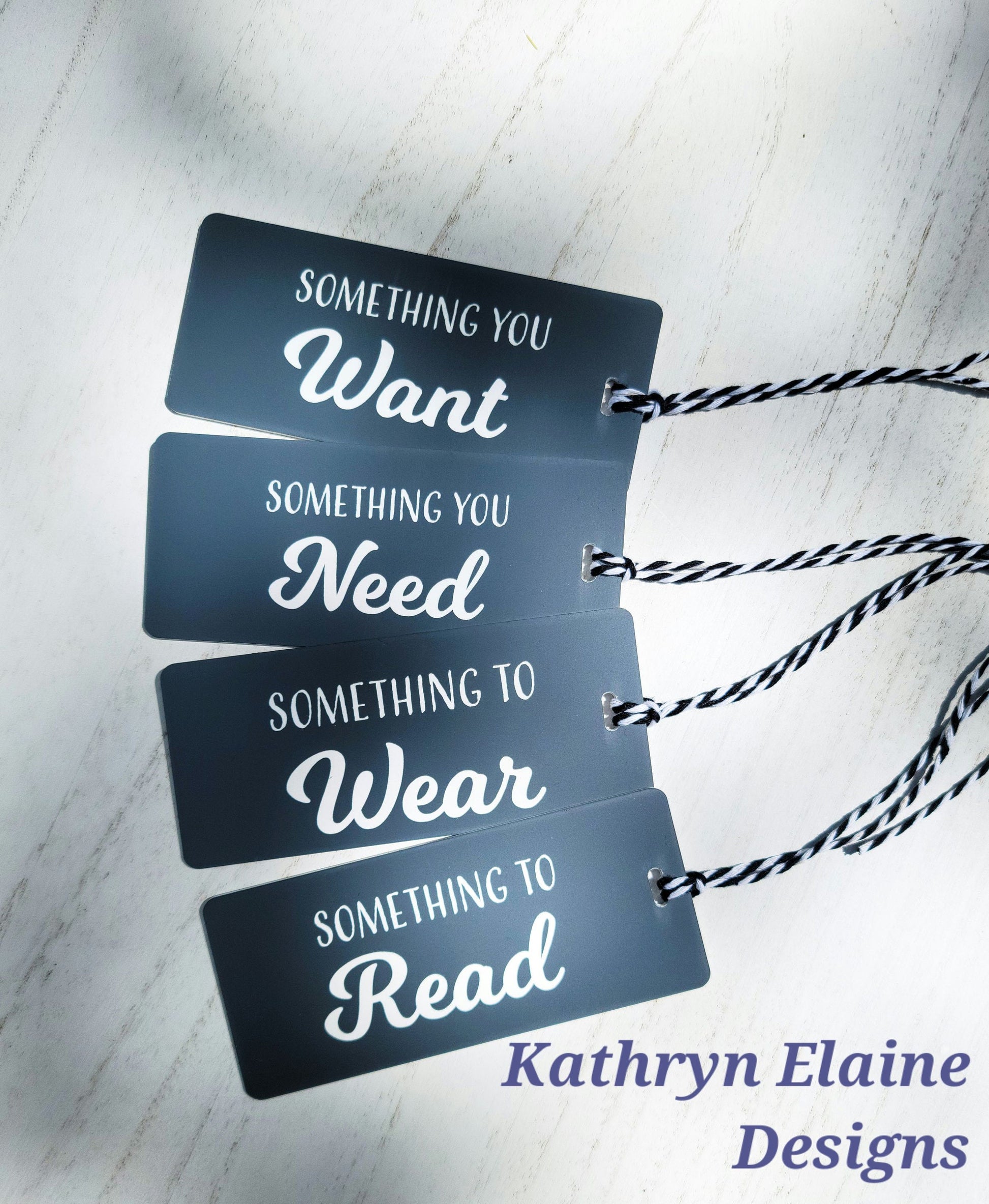 4 gift tags in black with white lettering reading something you want, something you need, something to wear, something to read on white background