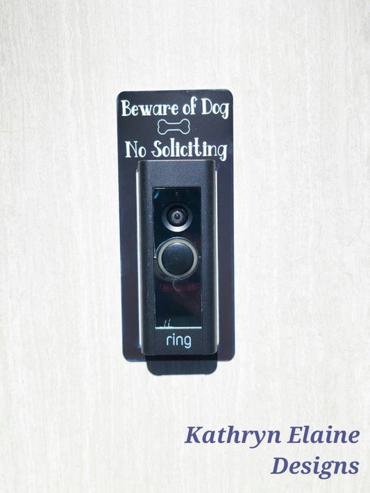 Black laminate doorbell surround stating Beware of Dog No Soliciting in white lettering with dog bone illustration against gray background
