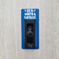 Blue laminate doorbell surround with white lettering stating red, white and blessed on gray background