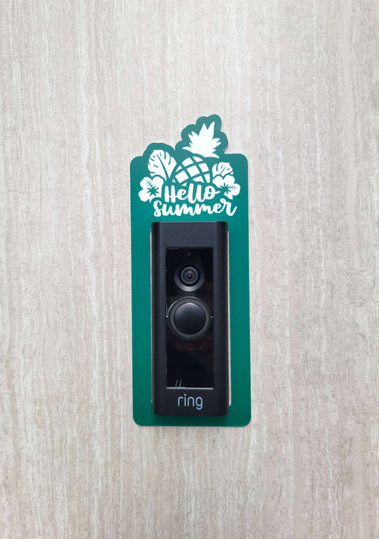 Green laminate doorbell surround with white pineapple, leaves, and flowers and lettering saying hello summer on ring doorbell and gray background